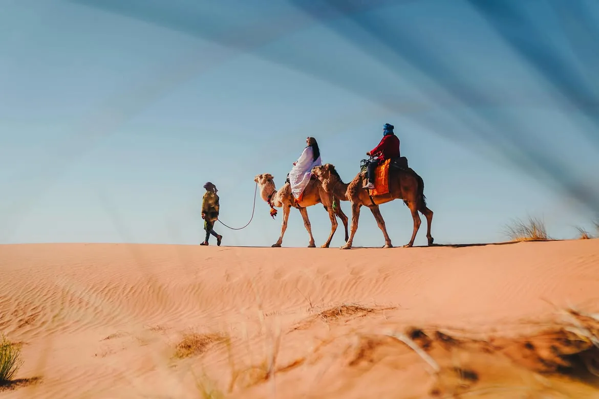 Viajeros en camello por las dunas del desierto de Marruecos